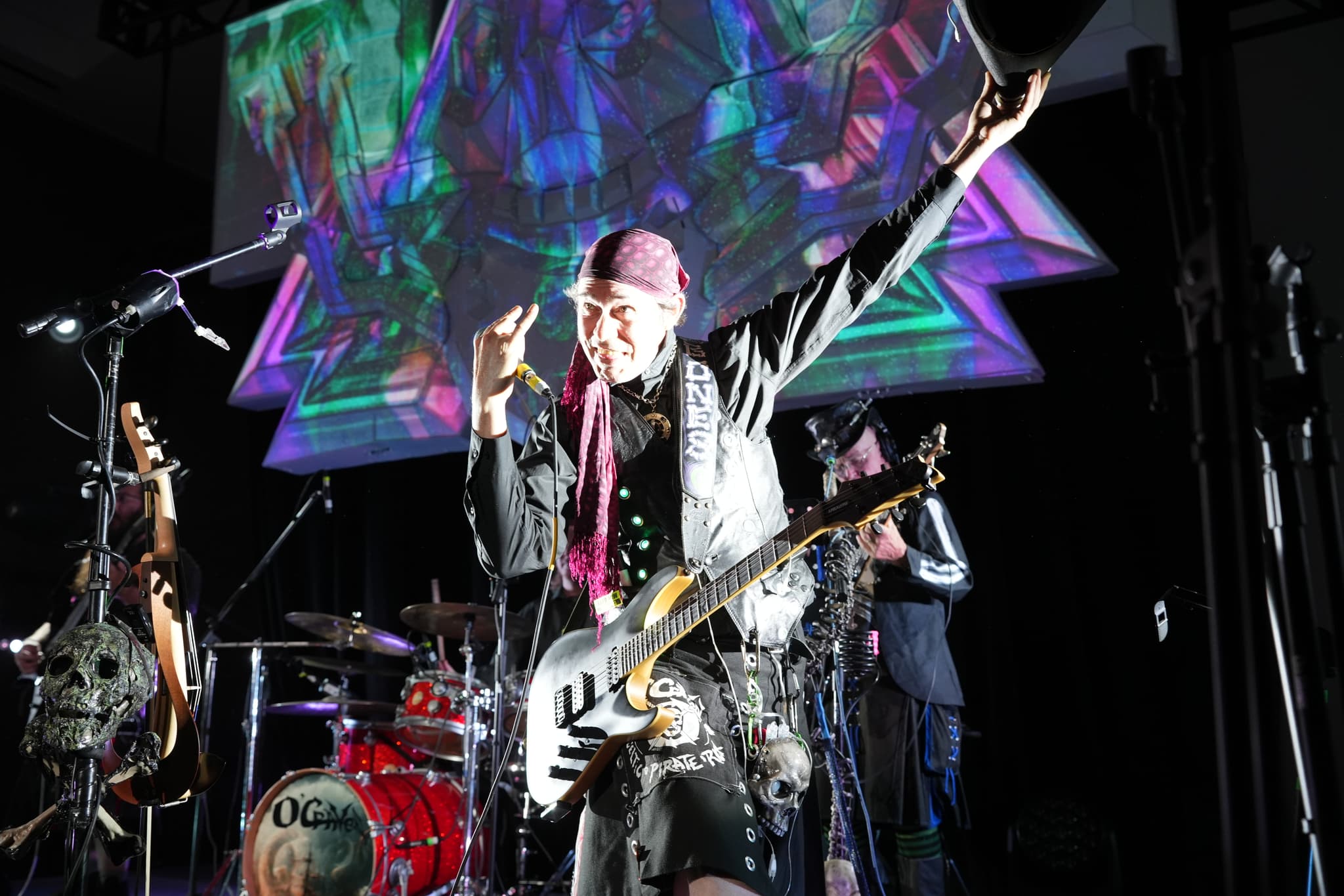 A musician on stage playing a guitar, with vibrant, colorful lights and a psychedelic backdrop