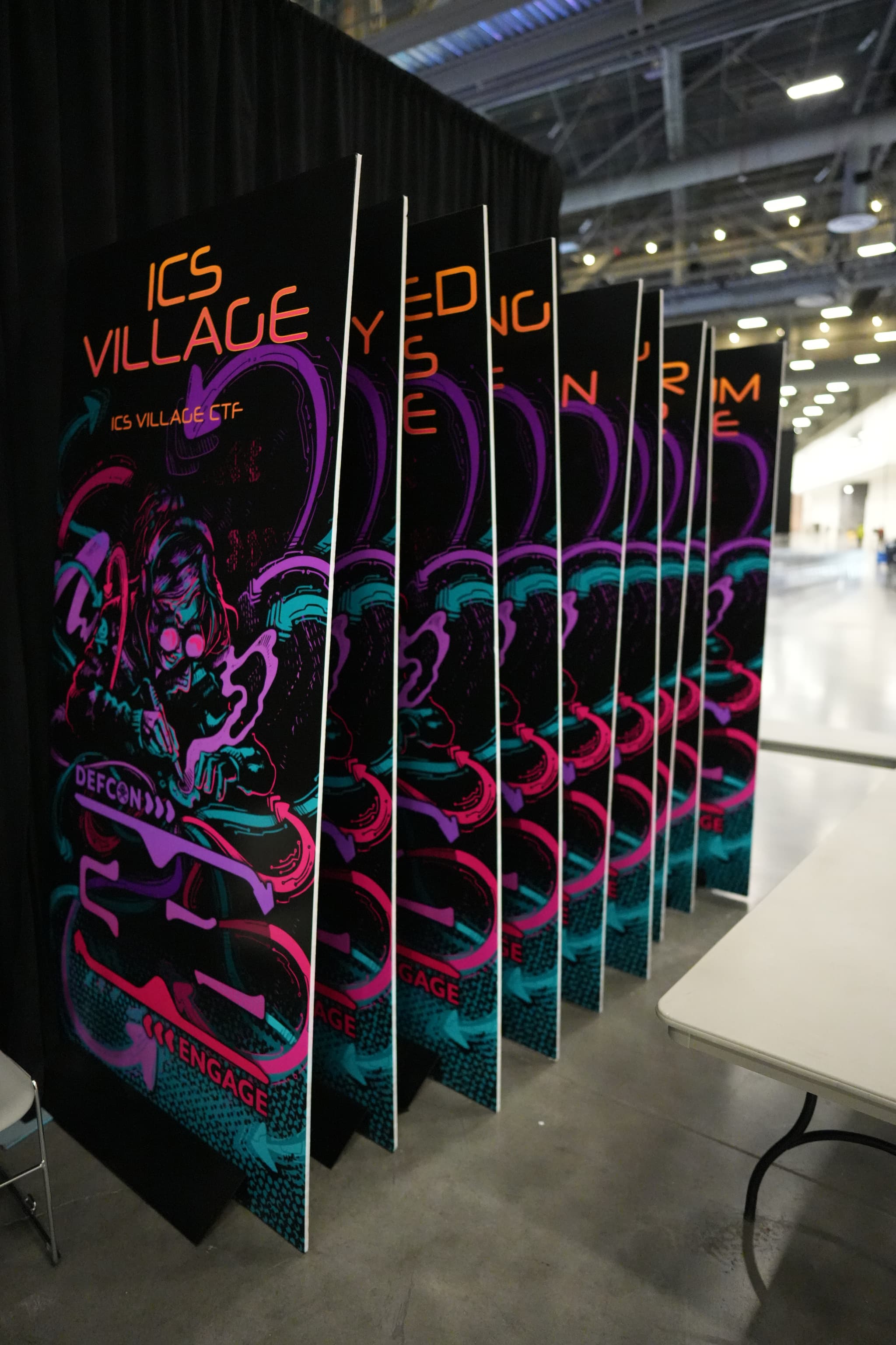 A series of vertical panels with neon artwork and the text ICS VILLAGE displayed in an indoor setting