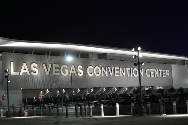 The Las Vegas Convention Center illuminated at night, with large, bold letters spelling out its name on the building's facade