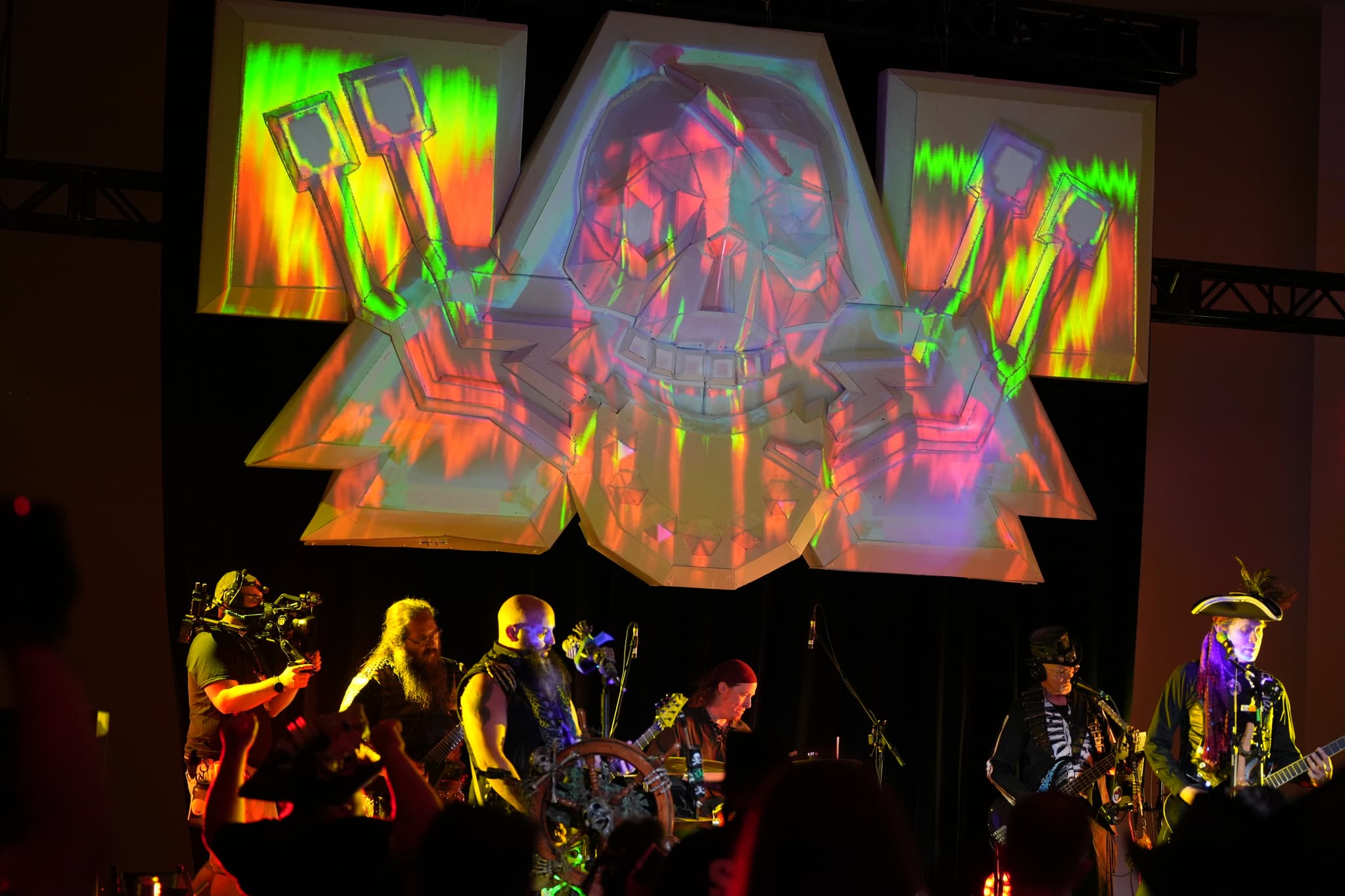 A band performing on stage with vibrant, colorful projections in the background